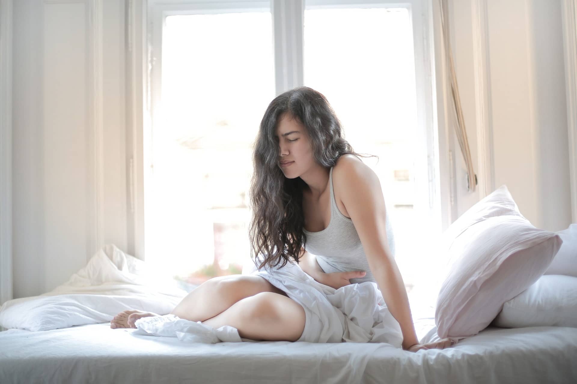 A beatiful girl in white clothes feel abdominal pain